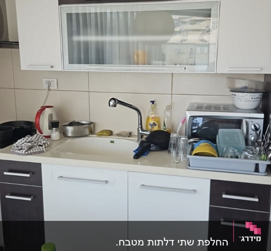 מטבח עם כיור, כלים ומכשירי חשמל על השיש